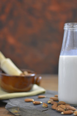 Homemade Almond milk in bottle with almonds in a bowl. Dairy alternative milk - close up with space for text