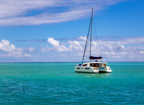 Lonely catamaran in a beautiful turquoise lagoon near the island Bora Bora in the Leeward group of the Society Islands of French Polynesia.