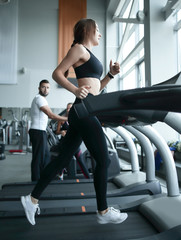 Fototapeta na wymiar side view. a young woman works on a treadmill in a fitness center