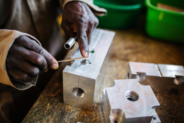 Fototapeta na wymiar Hands of a man working with tools in a workshop in Uganda, Africa.