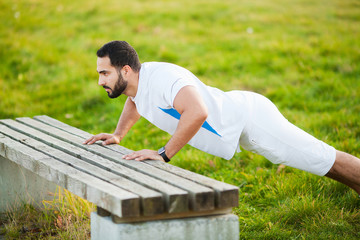 Fitness. Push-up exercise fitness man training arms muscles at outdoor gym