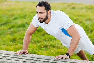Fitness. Push-up exercise fitness man training arms muscles at outdoor gym