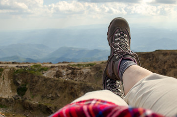 Legs in tracking shoes resting on a mountain field