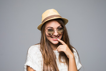 Closeup of beautiful young woman wearing straw hat and sunglasses on gray background