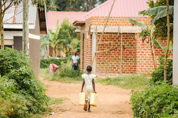 Fototapeta na wymiar Girl carrying water cans in Entebbe, Uganda