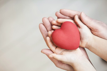 people, age, family, love and health care concept - close up of adult woman and child hands holding red heart over lights background. 