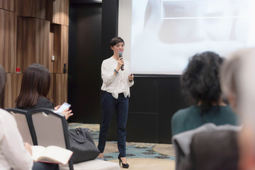 Beautiful business woman with microphone in her hand speaking at the  conference or seminar.;