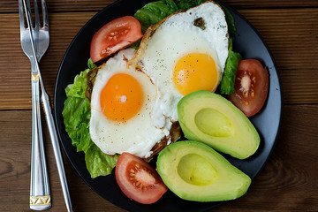 Healthy breakfast. Avocado, eggs sandwich with whole grain bread on wooden background. Copy space