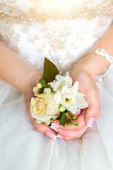 Bride's hands with a bouquet for the groom. place for text