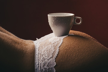 Morning. Sexy coffee. A cup of coffee on the naked female buttocks. Sexy ass. A young girl drinks...