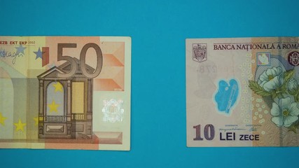 Romania to European Union integration process concept. close-up stop motion 4k footage video of Romanian lei money being covered merged with fifty euros on blue background