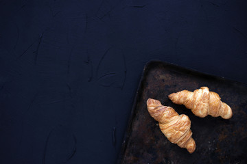 Fresh traditional french croissants on vintage dark background.Overhead view.Copy space