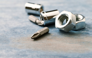 Bits for a screwdriver and hex nuts on wooden background. Close up. Copy space. 