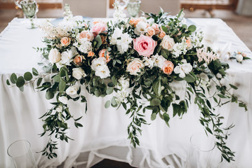 Amazing wedding decor with a lot of flowers. Wedding presidium for the newlyweds. Beautiful decor with pastel roses and greenery