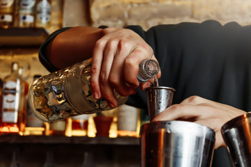 A barman pours alcohol into a shaker for a cocktail. Great plan.
