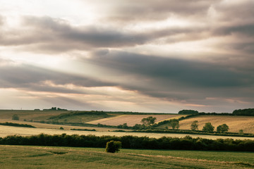 Obraz premium Sun Rays Through Clouds Over Countryside Fields