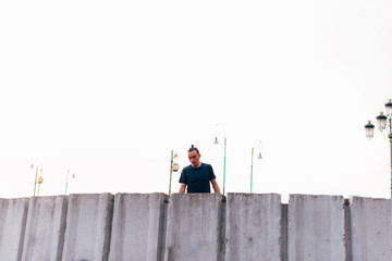 Fototapeta premium Caucasian man trains parkour while jumping over a high top.