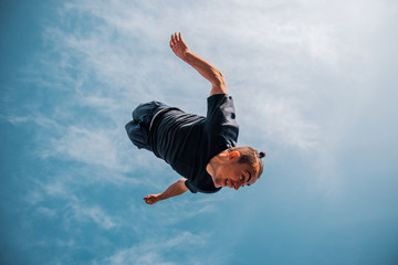Parkour guy jumping below blue sky