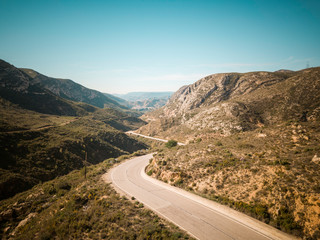 aerial mountains road panorama. Breathtaking curves perfect for motorcyclists or a car trip. On one side an asphalt road and on the other a dirt road, offroad.