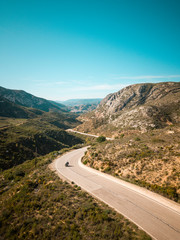 aerial mountains road panorama. Breathtaking curves perfect for motorcyclists or a car trip. On one side an asphalt road and on the other a dirt road, offroad.