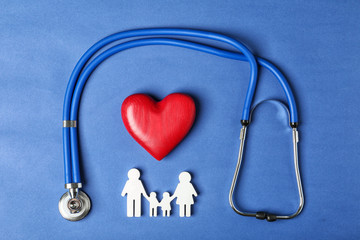 Flat lay composition with heart, stethoscope and family figure on color background. Life insurance concept