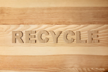 Word "Recycle" made of cardboard letters on wooden background, top view