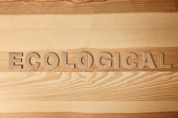 Word "Ecological" made of cardboard letters on wooden background, top view