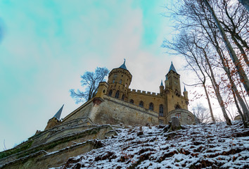 Medieval castle on the hill, mountains, trees and pines, beautiful trees, against the blue sky and white clouds