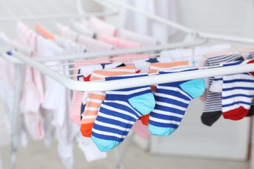 Different colorful socks on drying rack against blurred background, closeup