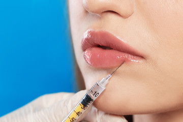 Young woman getting lips injection on color background, space for text. Cosmetic surgery