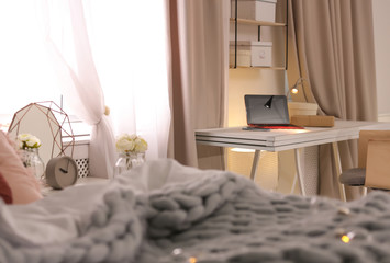 Workplace with laptop and bed in stylish apartment. Room interior