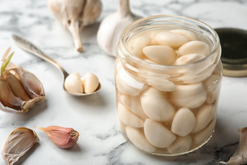 Preserved garlic in glass jar on table, closeup. Space for text