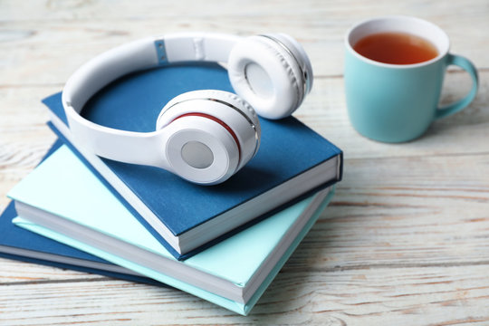 Modern headphones with hardcover books on wooden table