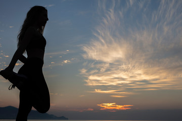 young woman does exercise at sunrise