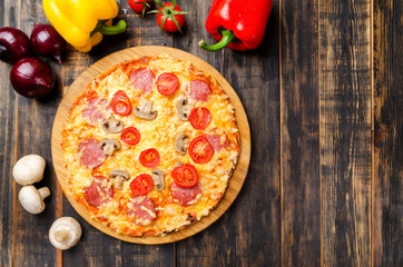 homemade pizza with tomatoes and mushrooms on a wooden table with vegetables
