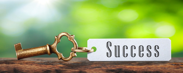 Old Brass Key And Tag With The Word Success On Wooden Table With Green Background - Business / Financial Success Concept