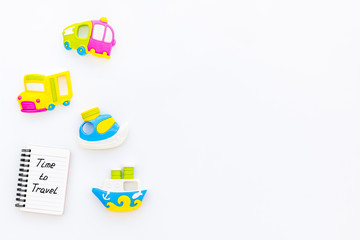 Time to travel. Accessories for treveling with children, toys and notebook on white background top view mock-up