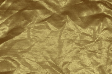 Luxury gold textile background. Silk cloth texture. Fabric pattern.