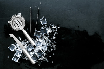 crashed ice cubes with barman tools on black kitchen table top view mock up