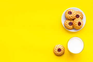 Drink milk with cookies concept. Cup of milk and fresh homemade cookies on yellow background top view copy space