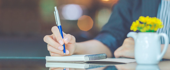 Business woman writing on a notebook.with a pen in the office.Web banner.