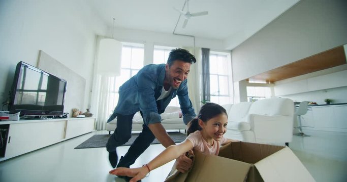 Portrait of happy father and daughter having fun in living room in slow motion. Shot with RED camera in 8K. Concept of happy family, childhood, parenthood