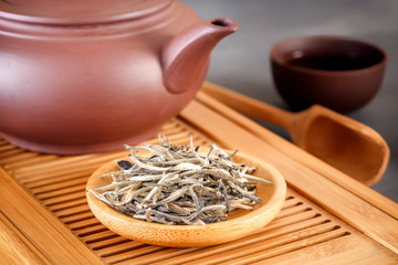 green tea and attributes for tea ceremony - a ceramic teapot, cups, a strainer, chopsticks and tweezers are placed on an old wooden table. Close-up