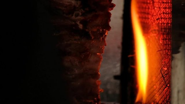 Traditional Turkish food Doner Kebab. Turnspit skewing kebap or kebab on metal skewer in the kebab restaurant. Shawarma meat being cut before making a sandwich. Shawarma meat cooking and turning