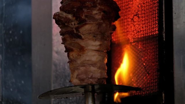Traditional Turkish food Doner Kebab. Turnspit skewing kebap or kebab on metal skewer in the kebab restaurant. Shawarma meat being cut before making a sandwich. Shawarma meat cooking and turning
