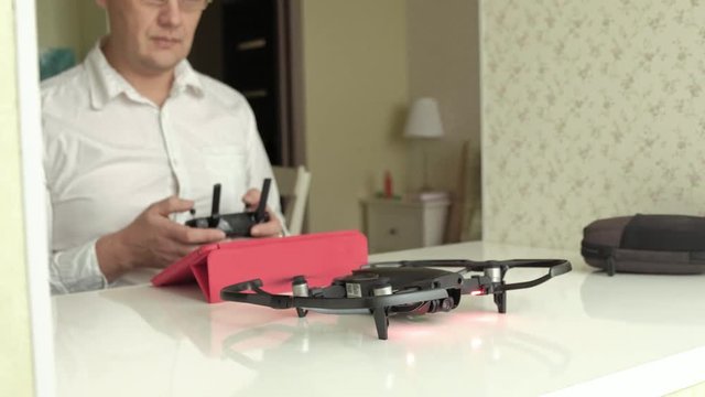 mature man in glasses and white shirt controls quadcopter from the console, test flight, the concept of studying technology