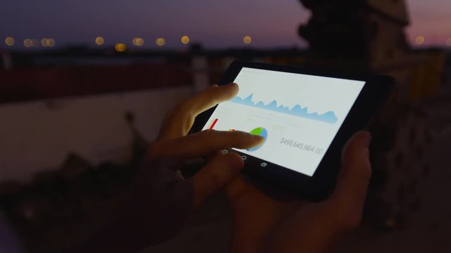 Businessman working on mobile platform outdoors managing a project Application using graphic charts looking at the data pies and vectors graphics