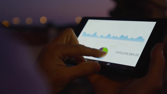 Businessman working on mobile platform outdoors managing a project Application using graphic charts looking at the data pies and vectors graphics