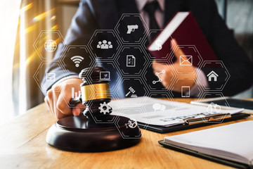 Justice and law concept.Male judge in a courtroom with the gavel, working with, digital tablet computer and smartphone docking keyboard, eyeglasses, on table in morning light