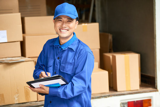 Portrait Of Cheerful Young Delivery Man With Digital Tablet Smiling At Camera